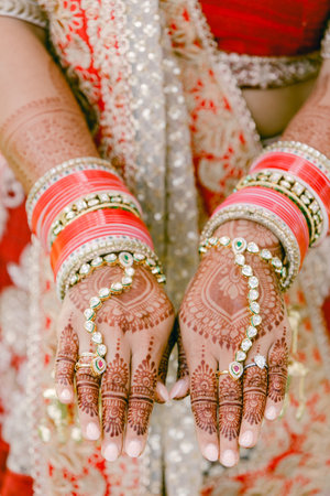 Hands with intricate mehndi and vibrant bangles showcase cultural traditions at an Indian wedding.の写真素材