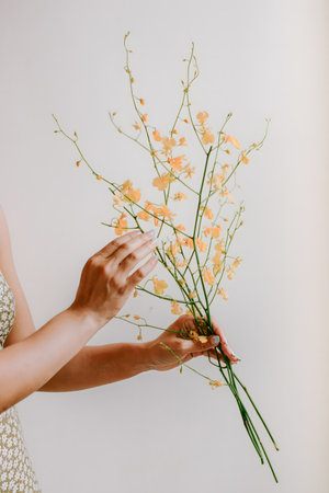 A woman gently holds and arranges a bouquet of delicate yellow flowers, creating a serene atmosphere...