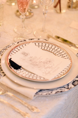 Beautifully arranged table featuring decorative plates, cutlery, and a menu card, perfect for a formal dinner gathering.の写真素材