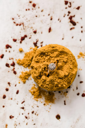 A stunning wedding ring rests on a dessert adorned with golden spices and red berries in the...
