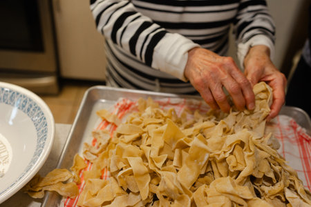 Hands skillfully shape freshly made pasta in a warm kitchen, showcasing a traditional culinary technique.の写真素材