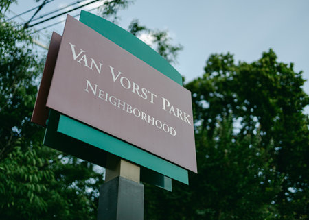 A park sign indicates the entrance to Van Vorst Park, surrounded by lush greenery in Jersey City...
