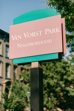 A sign indicating the neighborhood with lush greenery and historic buildings in the background on a clear day.の写真素材
