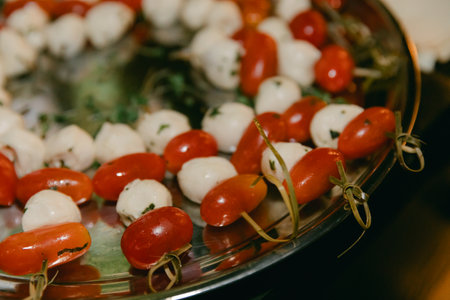 Fresh cherry tomatoes and mozzarella balls arranged beautifully for a vibrant appetizer at a summer gatheringの写真素材