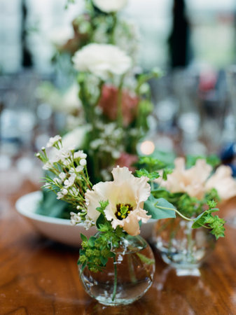 Beautiful floral arrangements feature soft colors and greenery on a dining table for a special...