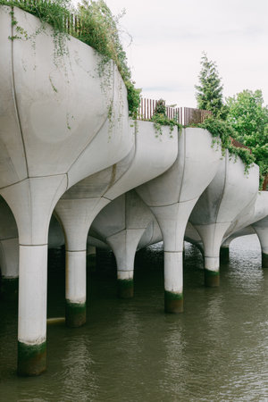An elevated walkway on unique concrete pillars offers a striking view along the urban riverside.