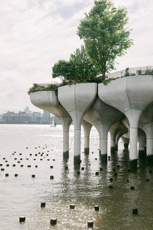 A concrete structure rises above water, adorned with greenery, providing a peaceful urban retreat.の写真素材