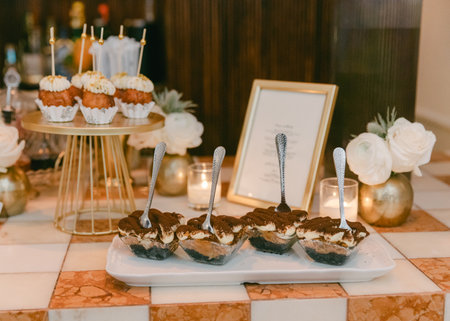 A beautiful arrangement of cupcakes and tiramisu cups at a festive celebration, accented with candles and floral decor.の写真素材