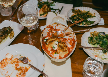 Guests savor a variety of dishes and wine in a warm, inviting setting, highlighting a shared...