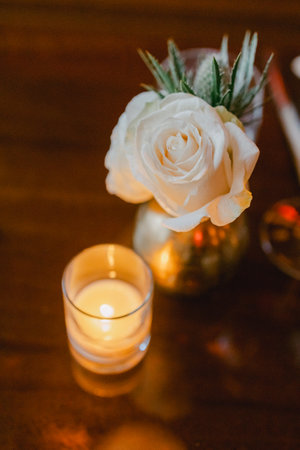 A white rose in a vase and a glowing candle create a warm ambiance for an evening gathering at a cozy table.の写真素材