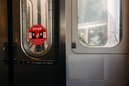 A red stop sign is visible on a subway door, highlighting safety measures for passengers during the day.の写真素材