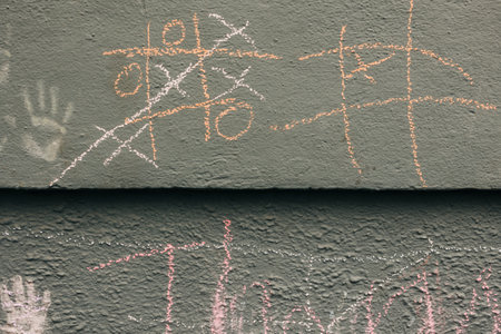 Kids play tic-tac-toe with chalk on a textured wall in the playground in the afternoon.の写真素材