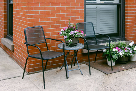 Colorful flowers adorn the patio table and nearby pots, creating a welcoming spot for relaxation and...