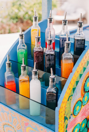 A vibrant display of various flavored syrups in glass bottles catches attention in an outdoor setting.の写真素材