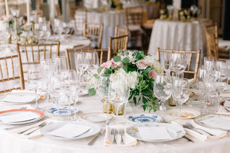 Beautifully arranged dining table features a lush floral centerpiece and elegant tableware for a...
