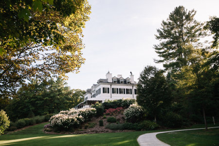 A stunning mansion on a hill is surrounded by trees and vibrant flowers, creating a serene atmosphere.の写真素材