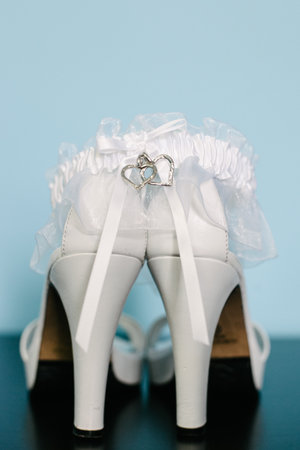 White high heels with a delicate garter featuring a heart charm, perfect for bridal wear on a special wedding day.の写真素材