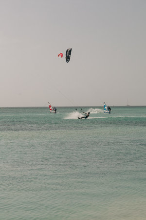 Kitesurfers glide over turquoise waters under a bright sky, showcasing their skills and enjoying the...