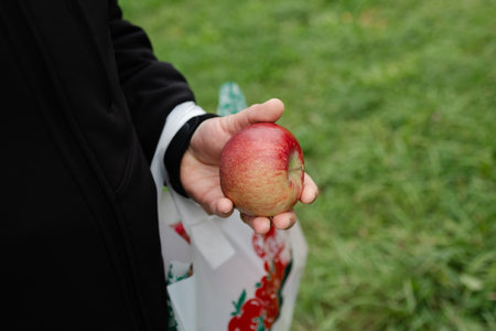 A person enjoys the beauty of nature while holding a freshly picked apple in a lush orchard during...