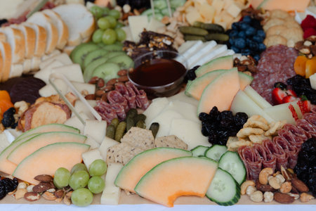 A colorful array of cheeses, cured meats, fresh fruits, and nuts is presented for guests at an...