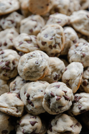 Batches of freshly baked chocolate chip cookies piled high on a cooling rack, showcasing a tempting...