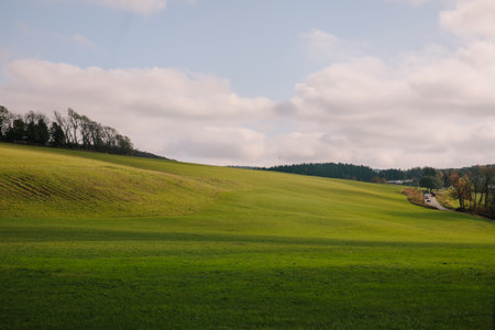Lush green hills stretch into the distance, dotted with trees against a bright afternoon sky.