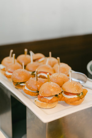 Neatly arranged mini sliders on a platter feature varied fillings, ideal for stylish catering events.の写真素材