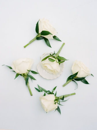 Five elegant white roses with green leaves are tastefully arranged, perfect for enhancing a special...