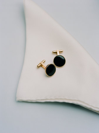 Black cufflinks are placed neatly on a white cloth napkin, suggesting an upcoming formal gathering.