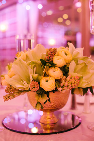 Elegant floral centerpiece adorned with yellow ranunculus at a festive evening event in a decorated venueの写真素材