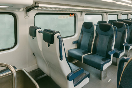Empty train interior showcasing comfortable seats and large windows allowing natural light during...