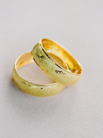 Two engraved gold wedding bands on cream fabric, symbolizing love and commitment in a tranquil setting.の写真素材