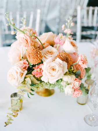 A beautiful floral centerpiece showcases an array of soft-colored roses and unique blooms, enhancing the stylish table.の写真素材