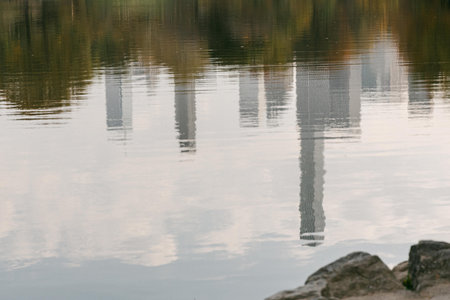 Buildings are reflected in the still water of the lake as dusk settles, creating a tranquil atmosphere in nature.の写真素材