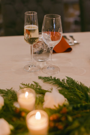 Sparkling drinks and a still glass grace a candlelit table with winter greenery, ideal for a cozy gathering.の写真素材