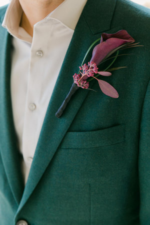 A groom in a tailored green suit and bright boutonniere, perfect for a spring wedding.