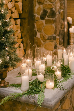 Warm atmosphere created by glowing candles and festive greens near a stone fireplace, perfect for winter celebrations.の写真素材