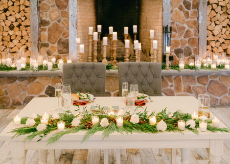 A beautifully arranged dining table with greenery and candles, perfect for a special celebration in a warm setting.の写真素材