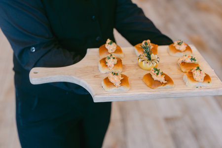 Waiter serves delicious seafood appetizers garnished with herbs at a stylish gathering in a modern setting.の写真素材