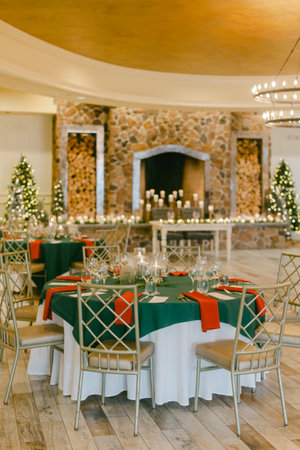 Tables are set for a holiday gathering, lit by candles and decorated with Christmas dÃ©cor.の写真素材