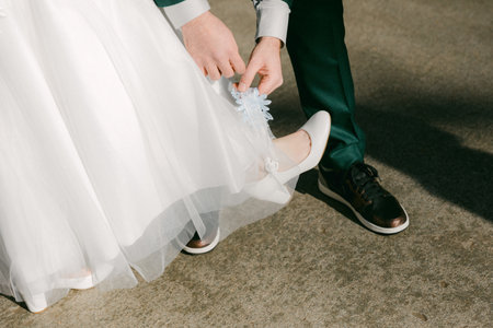 Groom carefully adjusts the bride's dress as they prepare for their wedding ceremony, surrounded by natural beauty.の写真素材
