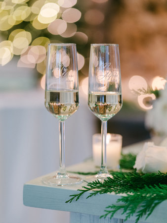 Two elegant champagne glasses filled with sparkling drink shine in a festive atmosphere with soft lights.の写真素材