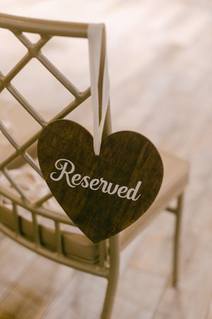 A heart-shaped sign labeled reserved hangs from a wooden chair in a serene, elegantly decorated space.の写真素材