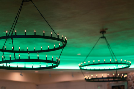 Brightly lit chandeliers add charm to a stylish dining space with green hues creating a cozy atmosphere for guests.の写真素材