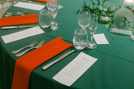 Table is beautifully set with glassware, cutlery, and orange napkins for a special dining experience.の写真素材