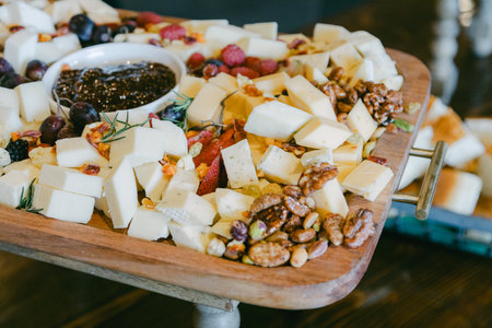 A vibrant cheese board features a variety of cheeses paired with nuts and fresh fruits in a cozy venue.の写真素材