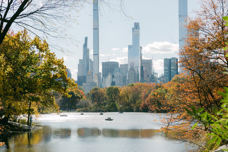 Kayakers enjoy a peaceful moment in Central Park surrounded by colorful fall foliage and towering skyscrapers.の写真素材