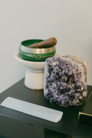 A collection of healing crystals and meditation tools arranged on a black surface, creating a serene...