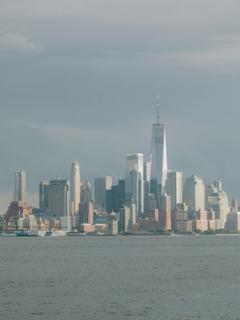 Manhattan skyline showcases modern architecture under overcast skies with calm waters in the...