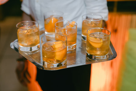 Waiter presents a tray of refreshing cocktails garnished with orange slices at a lively evening...